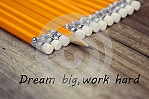 Work hard dream big motivational education message. Rustic wooden background with yellow pencils.