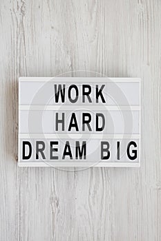 `Work hard dream big` words on a modern board on a white wooden background, top view. Flat lay, overhead, from above