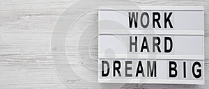 `Work hard dream big` words on a modern board on a white wooden background, top view. Flat lay, overhead, from above. Copy space