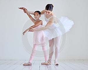 Work hard to get what you want out of your performance. a little girl practicing ballet with her teacher in a dance