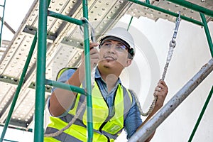 During work at a height, a construction worker wears a safety harness belt. on a background of a drilling platform for a