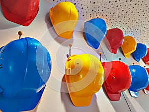 Work helmets of different colors hang on hooks on the wall.