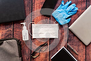 Remote work kit on wooden office desk with hand sanitizer and face mask, a solution against the spread of corona virus for photo