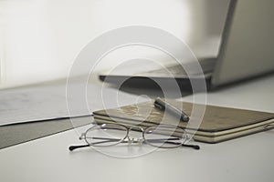 work from home, a glasses above laptop computer on a white modern business office desk