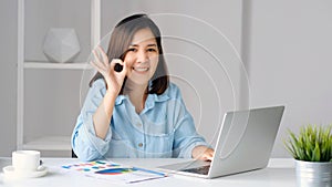 Work from home, Happy asian women working with laptop computer at home office and showing ok hand sign, Asia female with okay hand