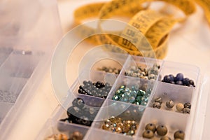 Work from home lifestyle concept: close-up detail of an organizer with various colored stone and crystal beads in foreground and a