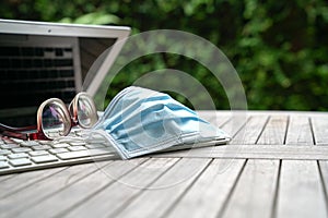 Work at home. Medical face mask on top of computer laptop with spectacles