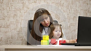 Work at home. in the room, mom works at the table with her little daughter at the computer. business woman working in