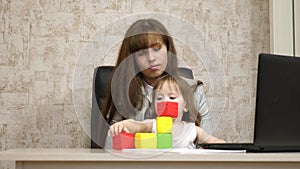 Work at home. in the room, mom works at the table with her little daughter at the computer. business woman working in