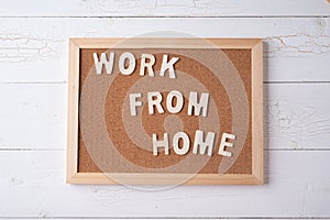 `Work from Home` words on a modern board on a white wooden surface, top view. Overhead, from above, flat lay