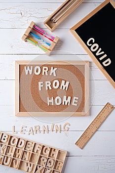 `Work from Home` words on a modern board on a white wooden surface, top view. Overhead, from above, flat lay