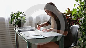 Work at home. young beautiful freelancer woman is working at the table by the window in the house. modern ecological