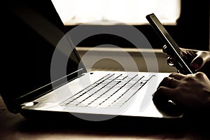 Girl`s hands on the computer and on the phone