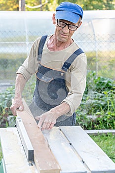 Work on the infield. Do it yourself. A carpenter processes wooden boards on the street using an electric woodworking