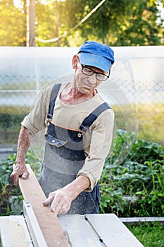 Work on the infield. Do it yourself. A carpenter processes wooden boards on the street using an electric woodworking