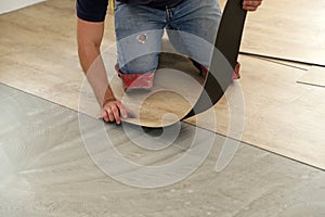 Work on laying flooring. Worker installing new vinyl tile floor.