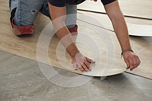 Work on laying flooring. Worker installing new vinyl tile floor.