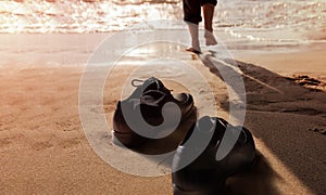 Work Life Balance Concept. Businessman take off his Working Shoes and leave it on the Sand Beach for Walk into the Sea on Sunny