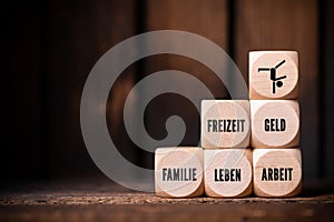 Work-life balance concept with the German words for FREETIME, MONEY, FAMILY, LIFE, WORK on wooden cubes