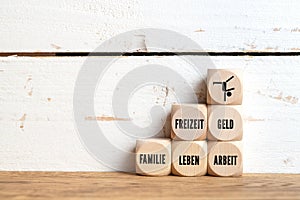 Work-life balance concept with the German words for FREETIME, MONEY, FAMILY, LIFE, WORK on wooden cubes