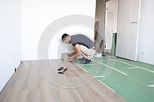 The work of a master floating flooring installation - installing laminate on the floor - male hands during work