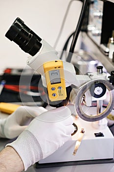 Work with a microscope. Microelectronics device. Close-up hands of a service worker repairing modern smartphone. Repair