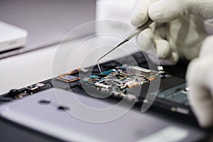 Work with a microscope. Microelectronics device. Close-up hands of a service worker repairing modern smartphone. Repair