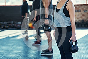 Work those muscles. a group unrecognizable people standing in a row doing training with weights in a gym.