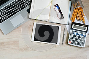 Work office desk table with laptop, tablet, supplies and calculator. Top view with copy space