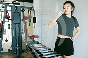 Work out concept asian female holding barbells in modern fitness
