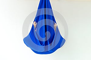 Work out on a hammock with a great yoga coach in the studio. Fly yoga. A girl sits in a lotus position in a blue anti-gravity yoga