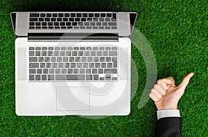 Work outdoors and businessman topic: human hands show the gestures in a black suit and an open notebook on a background of green