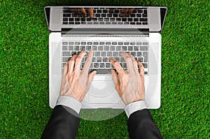 Work outdoors and businessman topic: human hands show the gestures in a black suit and an open notebook on a background of green g