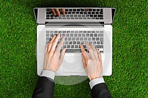 Work outdoors and businessman topic: human hands show the gestures in a black suit and an open notebook on a background of green g