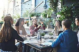 Work outside the box. Shot of a group of designers having a meeting at a coffee shop.
