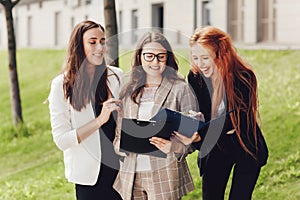 Work outside the office. Three successful caucasian businesswomen in suits standing on the street