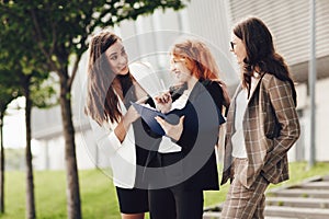 Work outside the office. Three successful caucasian businesswomen in suits standing on the street