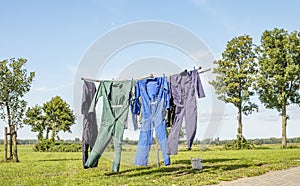 Laundry drying, work overalls hang on the line of the laundry rack with the clothes peg basket on a sunny summer day