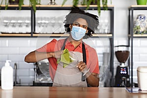 Work During Pandemic. Young black bartender wearing medical mask standing at bar counter