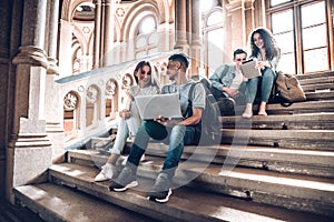 Work with the people that motivate and inspire you.Group of students studying while sitting on stairs in university