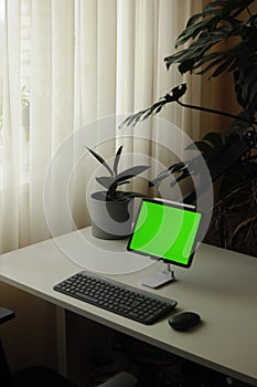 Work place at home with the tablet device. Minimalism style interior with plants