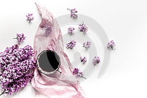 Work place with lilic flowers, coffee and scarf for woman on white desk background top view mock-up