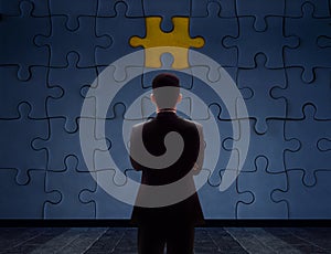Work Problem Concept. Blurred Back side of a businessman Standing in front of blank Jigsaw Puzzle Wall to Finding a Lost Piece. T