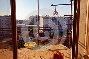 Work in progress on terrace with bricks, building under construction with scaffolding, tube for industry waste and industrial reel