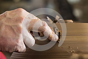 Work with red clay. Male hands form a bowl on a spinning pottery wheel.