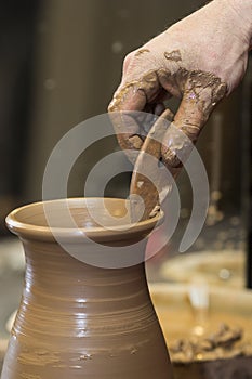 Work with red clay. Male hands form a bowl on a spinning pottery wheel.