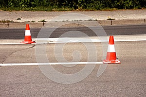 Work on road. Construction cones. Traffic cone, with white and orange stripes on asphalt. Street and traffic signs for signaling.