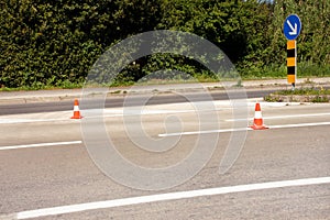 Work on road. Construction cones with traffic sign keep right sign. Traffic cones, with white and orange stripes on asphalt.