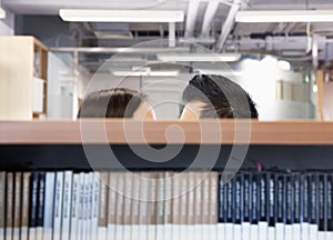 Work romance between two business people hiding behind shelves