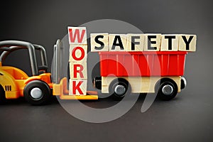 Work safety concept with wooden blocks on orange forklift with dark background